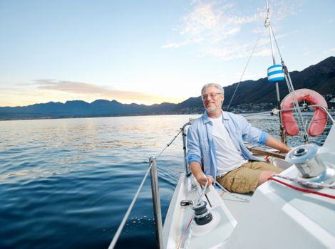 Ein Mann sitzt auf seinem Segelboot und blickt über das Wasser.